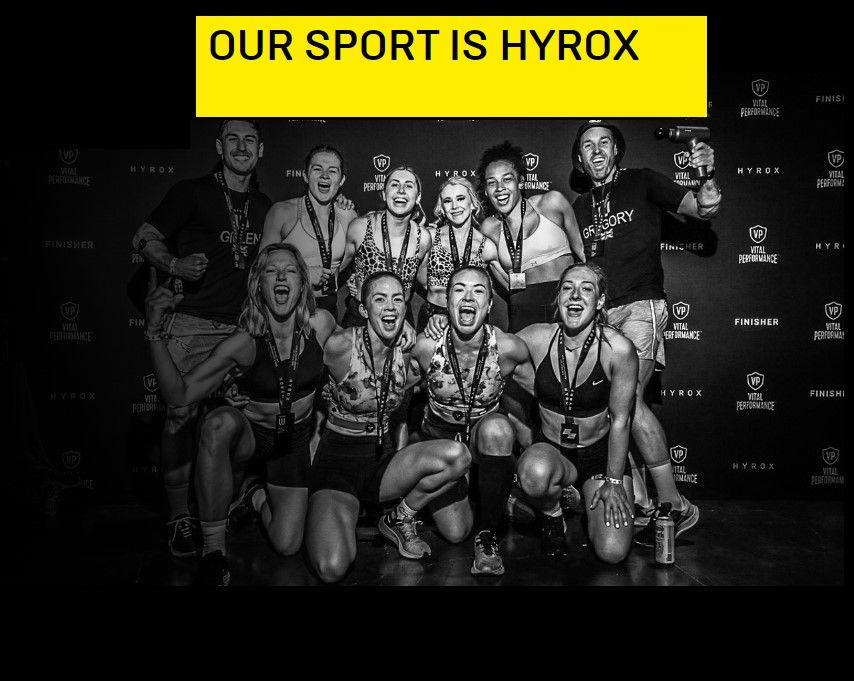 Group of athletes celebrating with medals, posing under a 'Our Sport is Hyrox' banner.